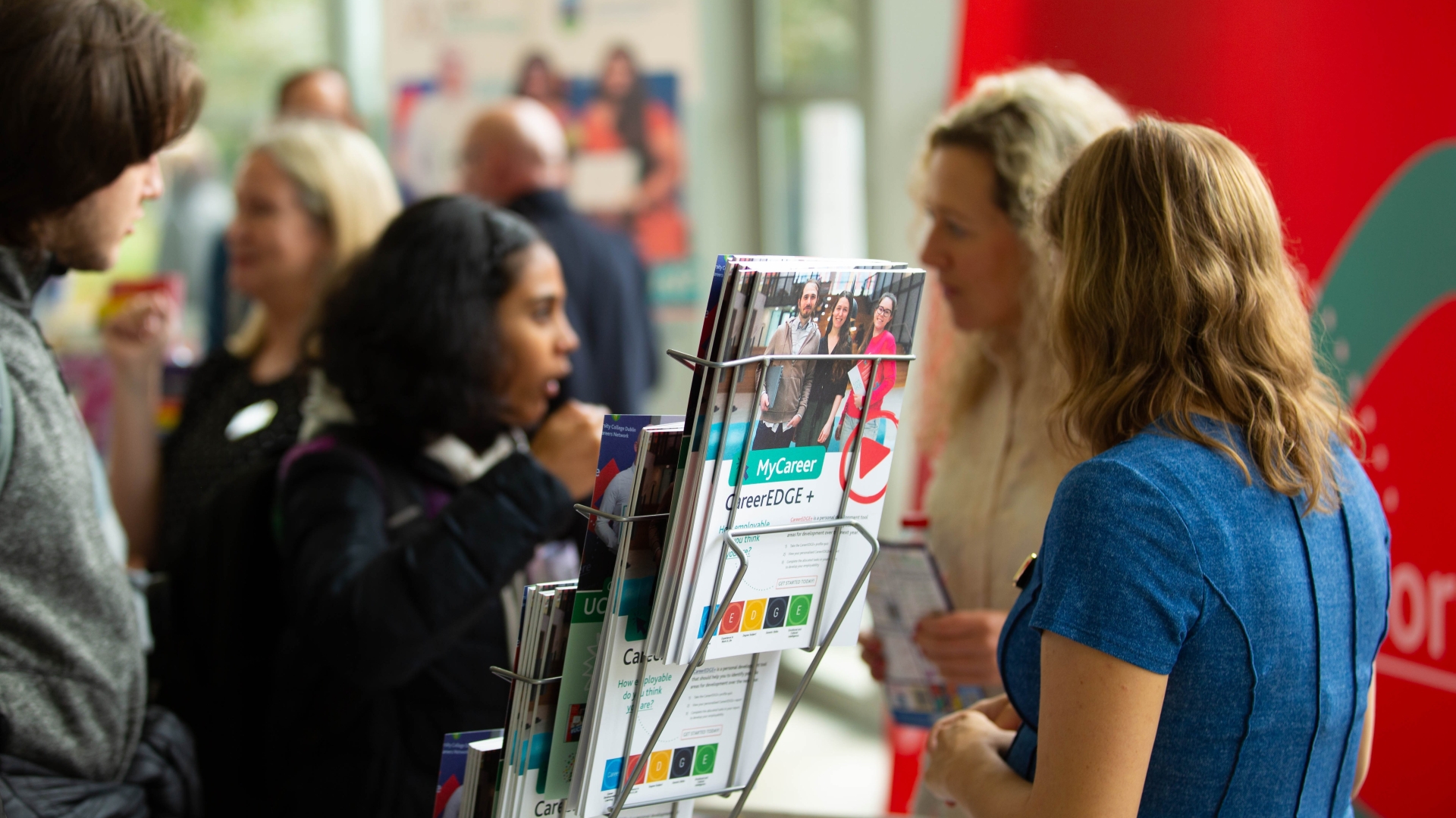 People chatting at a Careers Fair with some Careers Network leaflets in focus